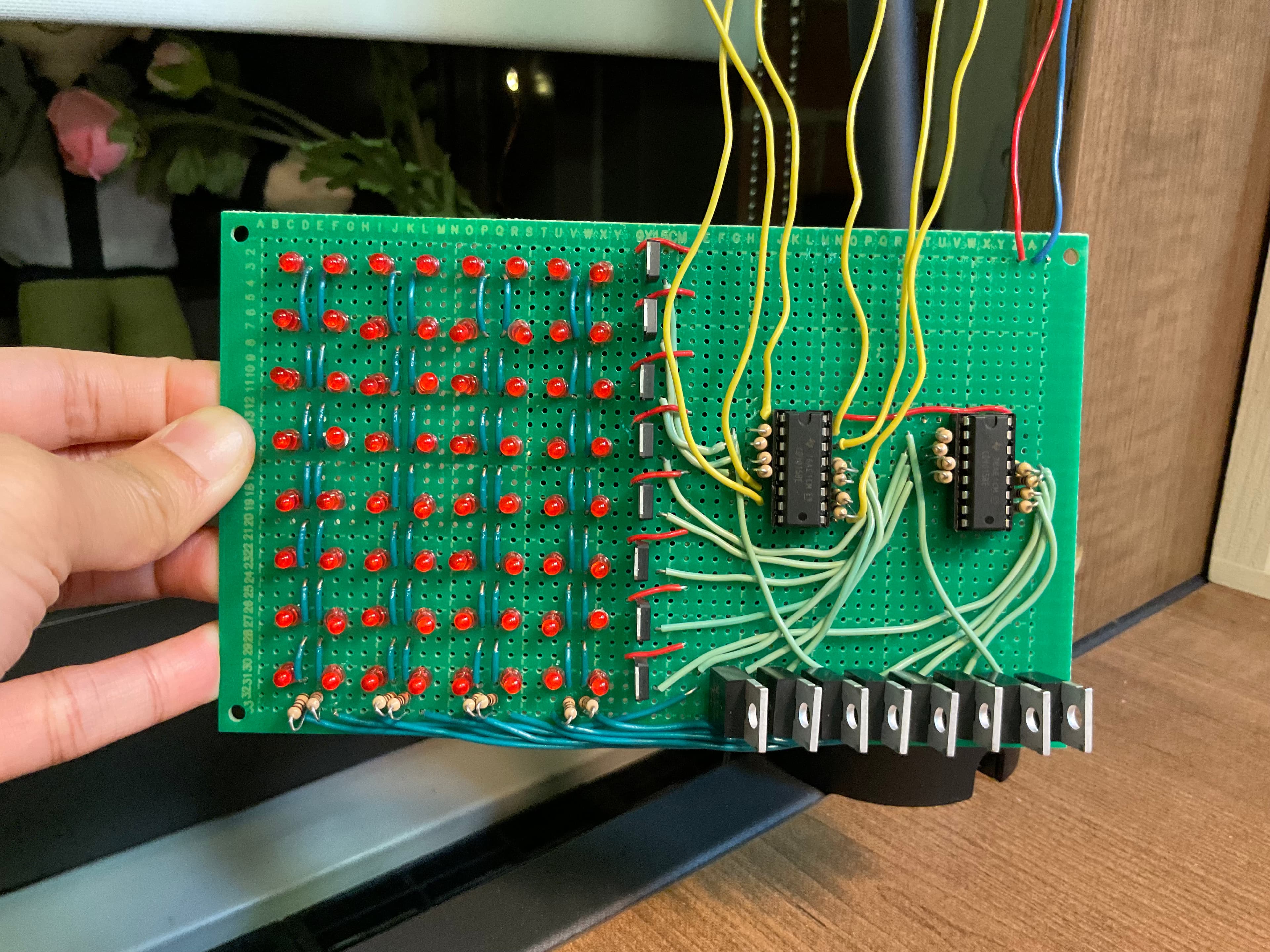 Hand-soldered 8x8 LED matrix, showing the row and column wiring on the back, the two shift-register ICs, and the row of MOSFET driver transistors