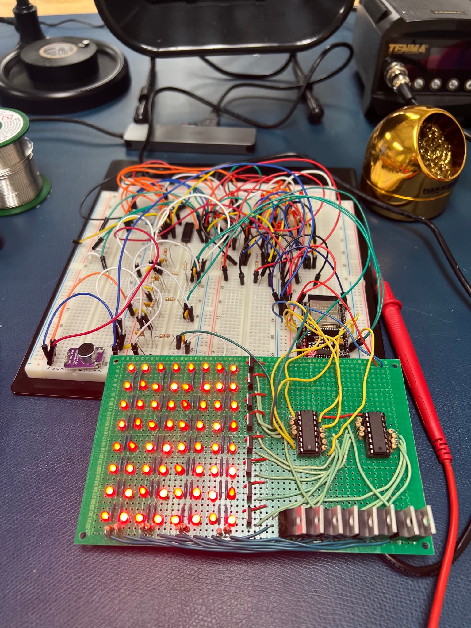 Complete circuit: the analog band-pass filter breadboard and ESP32 wired to the hand-soldered 8x8 LED matrix, lit mid-demo with a bar pattern across its columns