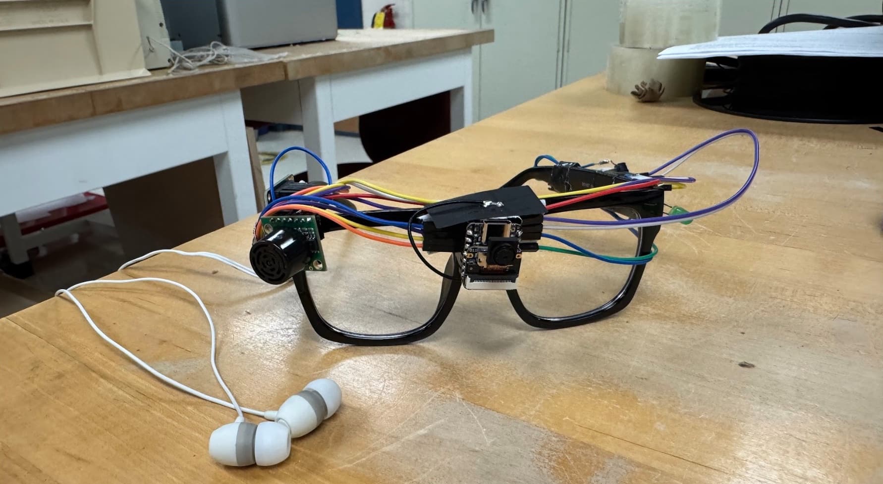 Assembled Guide Glasses prototype: camera, ultrasonic sensor, and wiring mounted onto a standard eyeglass frame